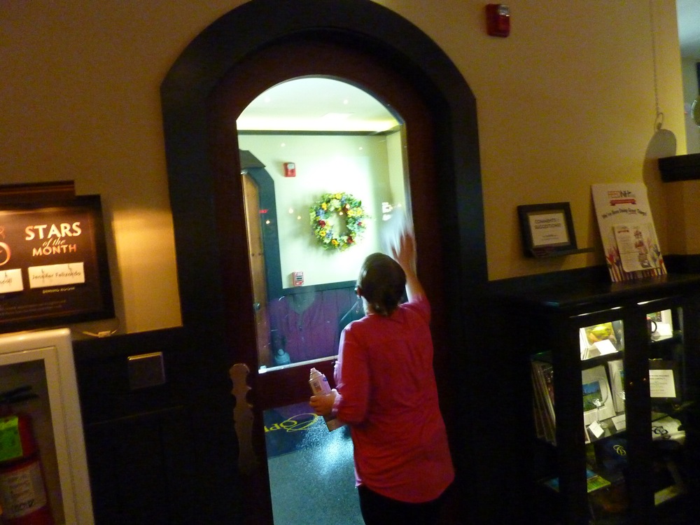 Employee pride at the Copper Door Restaurant in Bedford, NH; a manager cleans a door in between seating guests and overseeing management operations.