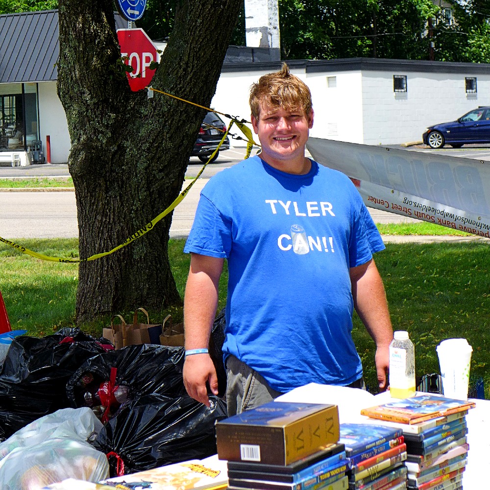 At the Walpole Farmers Market in Walpole, Mass.: Tyler Forgeron collects refundable bottles and cans and sells DVDs, and uses that money to donate to charitable and nonprofit organizations.